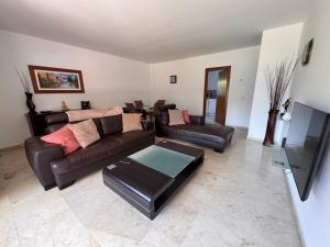 a living room with a leather couch and a table at Spacious ground floor apartment in Punta Prima
