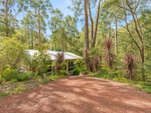 a home with a dirt road in front of a house at River Reach Chalet - Cosy Forest Hideaway in Margaret River Town