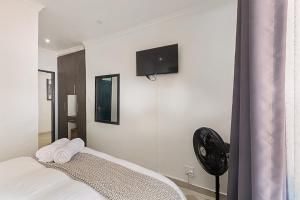 a bedroom with a bed with a fan and a tv on the wall at Elyon Suites in Kempton Park