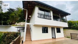 a white house with a balcony and a man standing outside at Apartamento La bonita guatape in Guatapé