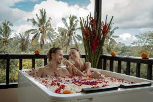 two people sitting in a bathtub covered in confetti at Nandini Jungle by Hanging Gardens in Payangan +45 photos