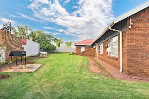 a yard next to a brick building with a lawn at Elyon Suites in Kempton Park