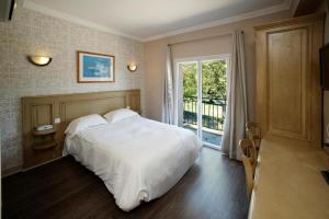 a bedroom with a large white bed and a window at Hotel du Lac & Restaurant Foix in Foix