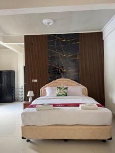 ein Schlafzimmer mit einem großen Bett und einem grünen Kissen in der Unterkunft Leokase Hotel in Dili