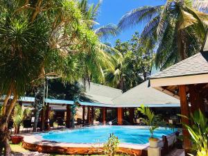 a large swimming pool with palm trees in front of a building at Paradise Garden Hotel and Convention Center Boracay Powered by ASTON in Boracay