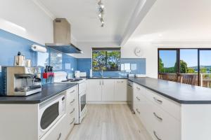 a kitchen with white cabinets and blue walls at Forsters Bay Haven in Narooma +5 photos