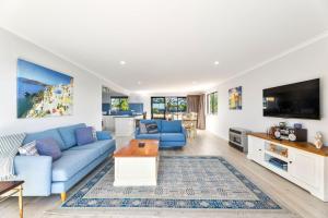 a living room with a blue couch and a tv at Forsters Bay Haven in Narooma