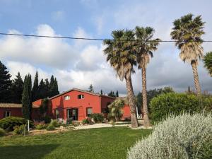 a red house with palm trees in a yard at Gite L olivier in Baho