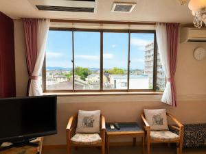 a room with a large window with two chairs and a table at 和洲館ホテル in Gyōda +8 photos