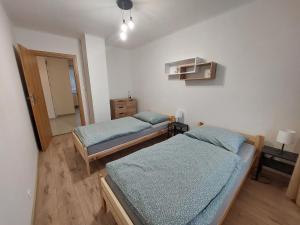 a bedroom with two beds and a hallway with a door at Penzión Ostrva in Vyšné Hágy