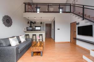 a living room with a gray couch and a staircase at Iris Apartment in Dalung