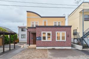 a red brick house with white windows on a street at 星宿 Sirius in Asahikawa