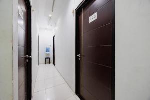 a hallway with two brown doors and a white tile floor at RedDoorz at Taman Galaxy Bekasi in Bekasi