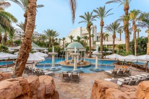 a resort pool with chairs and palm trees at Royal Garden by Isrotel Collection in Eilat