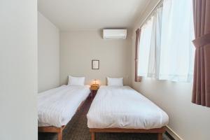 two twin beds in a room with a window at 星宿 Sirius in Asahikawa