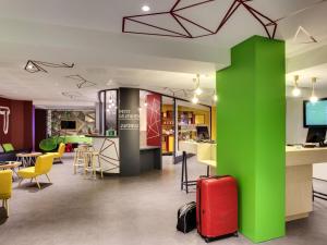 a room with a green pillar and a red suitcase at ibis Styles Nantes Centre Gare in Nantes