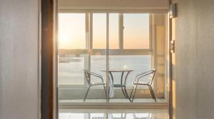 a table and chairs sitting on a balcony with a window at Pohang Pine Wave Pension in Pohang
