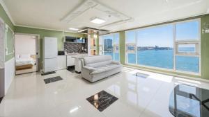 a living room with a white couch and a kitchen at Pohang Pine Wave Pension in Pohang
