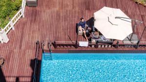 a man and a woman sitting under an umbrella next to a swimming pool at Daebudo (Yeongheungdo) Dunia Spa Pension in Incheon
