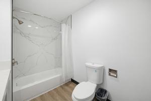 a white bathroom with a toilet and a shower at Hyland Inn Van Nuys in Van Nuys +55 photos