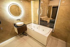 a bathroom with a tub and a sink and a mirror at Tiger Aura Resort in Rāmnagar +31 photos