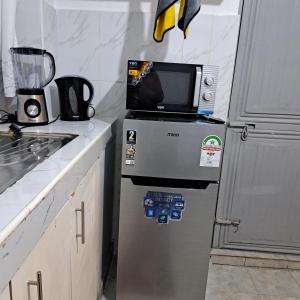 a microwave on top of a refrigerator in a kitchen at RyNa Homes in Meru