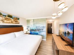 a bedroom with a large bed and a flat screen tv at Sea Edge Beachside Hotel in Parksville +100 photos