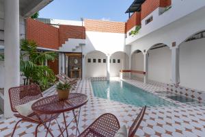 an outdoor patio with a swimming pool and tables and chairs at Baan Old Town Boutique Stay, Phuket Town in Phuket