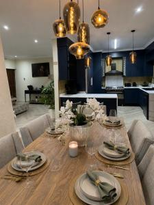 a dining room with a wooden table with plates and glasses at The Luxury Orchid in Pietermaritzburg