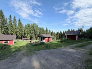 ein Feldweg vor zwei kleinen Gebäuden in der Unterkunft Metsäpirtti in Kolinkylä