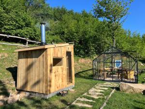 a wooden dog house and a greenhouse in a yard at Tenda Chirè in Garessio