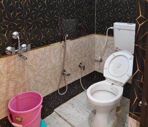 a bathroom with a toilet and a bucket at Hotel Ram Shankar - Saryu Ghat in Ayodhya