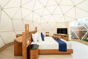 a bedroom in a geodesic dome with a bed and a tv at Triyana Resort and Glamping Carangsari Bali in Payangan