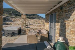 a patio with a table and chairs and a stone wall at Vigla View Sifnos in Vathi
