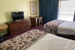 a hotel room with two beds and a desk and a television at Budgetel Inn & Suites in Yuma
