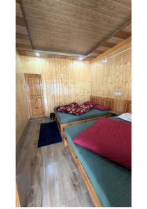 a room with two beds in a wooden cabin at Ekdantam Hotel and Restaurant in Uttarkāshi