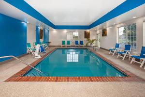 a pool in a hotel room with blue chairs and tables at La Quinta by Wyndham Springfield IL in Springfield