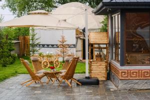 a group of chairs and an umbrella on a patio at Kurjun Guest House in Bokonbayevo