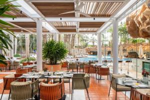 a restaurant with tables and chairs and a pool at Royal Beach Eilat by Isrotel Exclusive in Eilat