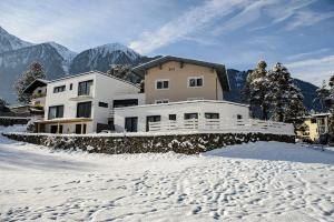Landhaus Ambachhof في أوتز: منزل في الثلج مع جبال في الخلف