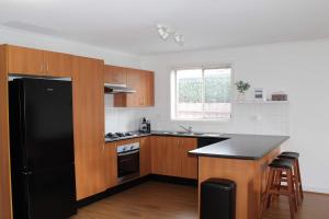 a kitchen with a black refrigerator and wooden cabinets at Sunbury on the Park in Sunbury