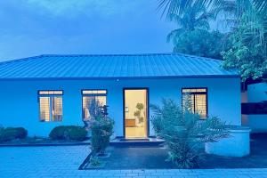 a blue house with a door and a palm tree at Triple A Gardens in Kollam