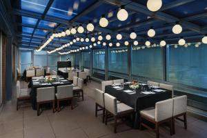 a dining room with tables and chairs and lights at Hyatt Place New York City - Times Square in New York