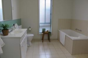 a bathroom with a tub and a toilet and a sink at Sunbury on the Park in Sunbury