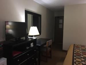 a hotel room with a television and a desk with a lamp at Super 8 by Wyndham New Castle in New Castle