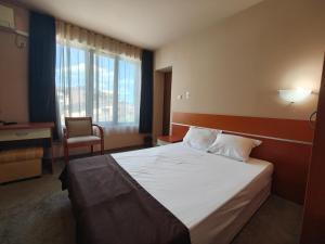 a bedroom with a bed and a desk and a window at Семеен хотел"Свети Георги" in Burgas