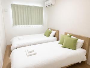 two beds in a room with white and green at Nakijin Terrace in Nakijin