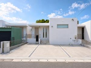 a white house with a parking lot at Nakijin Terrace in Nakijin