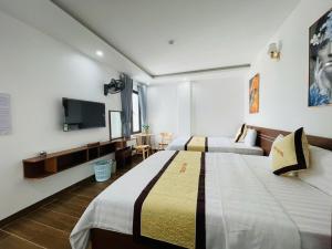 a hotel room with two beds and a tv at A90 HOTEl2 in Nhật Tựu