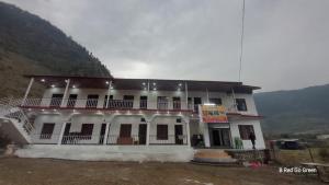a large white building with a mountain in the background at Swastik Hotel & Restaurant in Kharsālī +4 photos